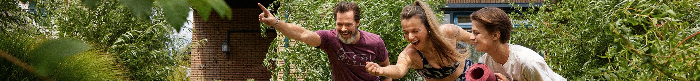 Een man, vrouw, en kind die buiten in de achtertuin yoga doen.